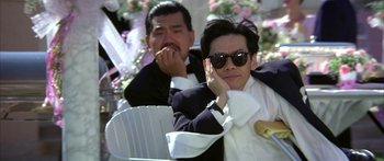 Movie still from “Twin Dragons” (1992), directed by Ringo Lam – A man in a suit sitting next to another man in a white suit; Medium shot, Low angle