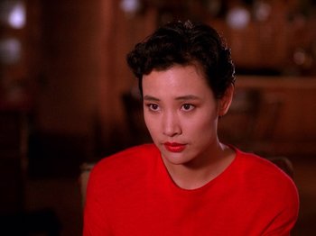 Movie still from “Twin Peaks” (1990), created by David Lynch – A woman in a red shirt is looking at the camera; Close Up shot, Over the shoulder angle