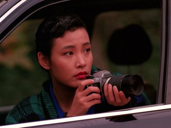 Movie still from “Twin Peaks” (1990), created by David Lynch – A woman taking a picture from inside a car; Close Up shot, High angle