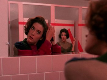 Movie still from “Twin Peaks” (1990), created by David Lynch – A woman in a bathroom looking in the mirror; Close Up shot, Over the shoulder angle