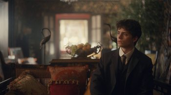 Movie still from “Anne with an E” (2017), created by Moira Walley-Beckett – A man in a suit sitting in front of a bowl of fruit; Medium shot, Over the shoulder angle
