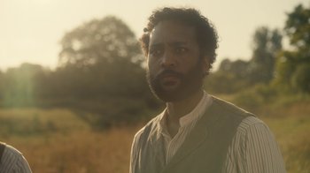 Movie still from “Anne with an E” (2017), created by Moira Walley-Beckett – A man with a goatee is standing in a field; Close Up shot, Low angle
