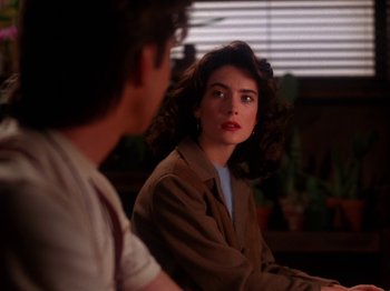 Movie still from “Twin Peaks” (1990), created by David Lynch – A woman sitting in front of a man in a brown jacket; Close Up shot, Over the shoulder angle