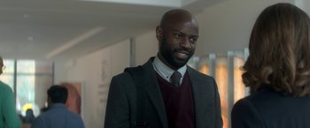 Movie still from “Annihilation” (2018), directed by Alex Garland – A man in a suit and tie smiling for the camera; Close Up shot, Over the shoulder angle