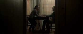Movie still from “Annihilation” (2018), directed by Alex Garland – Two people sitting at a table in front of each other; Medium shot, High angle