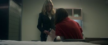 Movie still from “Annihilation” (2018), directed by Alex Garland – A woman in a red shirt and a woman in a black suit are looking at papers; Medium shot, Over the shoulder angle