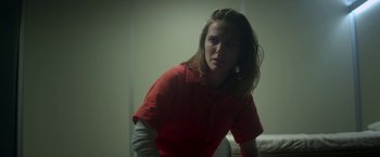 Movie still from “Annihilation” (2018), directed by Alex Garland – A woman in a red shirt is sitting in a room; Close Up shot, Over the shoulder angle