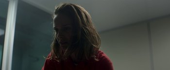 Movie still from “Annihilation” (2018), directed by Alex Garland – A woman in a red shirt is looking at the camera; Close Up shot, Over the shoulder angle