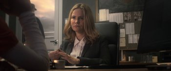 Movie still from “Annihilation” (2018), directed by Alex Garland – A woman sitting at a desk in a room; Medium shot, Over the shoulder angle