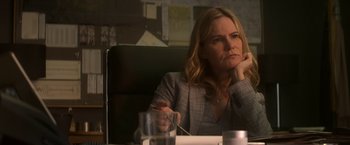 Movie still from “Annihilation” (2018), directed by Alex Garland – A woman sitting at a table with a glass in front of her; Close Up shot, Over the shoulder angle