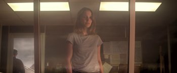 Movie still from “Annihilation” (2018), directed by Alex Garland – A woman standing in a dimly lit room; Medium shot, Low angle