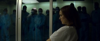 Movie still from “Annihilation” (2018), directed by Alex Garland – A woman standing in front of a group of people; Medium shot, Over the shoulder angle