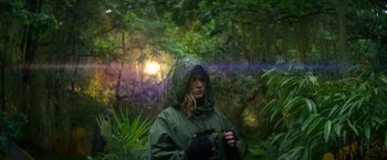 Movie still from “Annihilation” (2018), directed by Alex Garland – A woman in a green rain jacket standing in the woods; Medium shot, Low angle