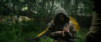Movie still from “Annihilation” (2018), directed by Alex Garland – A man in a hooded jacket standing in the rain; Medium shot, Low angle