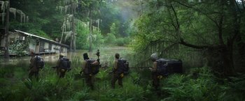Movie still from “Annihilation” (2018), directed by Alex Garland – A group of people in the woods with backpacks and guns; Wide shot, High angle