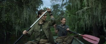 Movie still from “Annihilation” (2018), directed by Alex Garland – Two women are paddling a boat in the woods; Medium shot, Over the shoulder angle