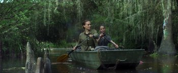 Movie still from “Annihilation” (2018), directed by Alex Garland – Two people in a boat on a river with trees in the background; Wide shot, Over the shoulder angle
