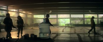 Movie still from “Annihilation” (2018), directed by Alex Garland – A person holding a water bottle in a room; Wide shot, Low angle
