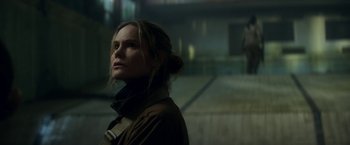 Movie still from “Annihilation” (2018), directed by Alex Garland – A woman standing in the dark with her head turned to the side; Close Up shot, Over the shoulder angle