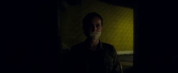 Movie still from “Annihilation” (2018), directed by Alex Garland – A person with a mouth taped shut in a dark room; Close Up shot, Over the shoulder angle