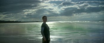 Movie still from “Annihilation” (2018), directed by Alex Garland – A woman standing in the water in front of the ocean; Wide shot, Low angle