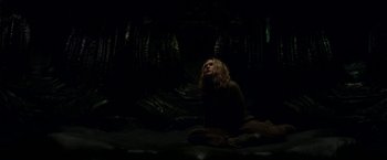 Movie still from “Annihilation” (2018), directed by Alex Garland – A person sitting on the ground in a dark room; Wide shot, Overhead angle