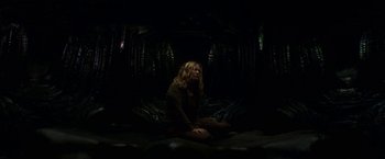 Movie still from “Annihilation” (2018), directed by Alex Garland – A woman sitting on the ground in a dark room; Wide shot, High angle