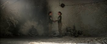 Movie still from “Annihilation” (2018), directed by Alex Garland – Two people holding hands in a room with smoke coming out of the wall; Wide shot, Overhead angle