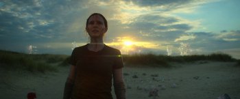 Movie still from “Annihilation” (2018), directed by Alex Garland – A woman standing on a beach with a sunset in the background; Medium shot, Low angle