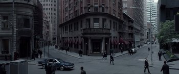 Movie still from “Anon” (2018), directed by Andrew Niccol – A group of people walking across a street near a building; Extreme Wide shot, High angle