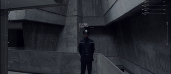 Movie still from “Anon” (2018), directed by Andrew Niccol – A man in a uniform standing in front of a building; Wide shot, Low angle