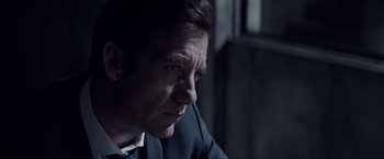 Movie still from “Anon” (2018), directed by Andrew Niccol – A person wearing a suit and tie; Close Up shot, Over the shoulder angle