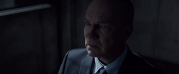 Movie still from “Anon” (2018), directed by Andrew Niccol – A man wearing a suit and tie looking at the camera; Close Up shot, Over the shoulder angle