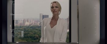 Movie still from “Anon” (2018), directed by Andrew Niccol – A woman standing in front of a window with a city view; Medium shot, Over the shoulder angle