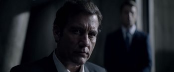 Movie still from “Anon” (2018), directed by Andrew Niccol – A person wearing a suit and tie; Close Up shot, Low angle