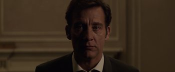 Movie still from “Anon” (2018), directed by Andrew Niccol – A person wearing a suit and tie; Close Up shot, Low angle