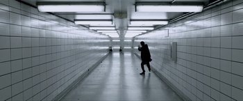 Movie still from “Anon” (2018), directed by Andrew Niccol – A person walking down a long hallway in a building; Wide shot, High angle