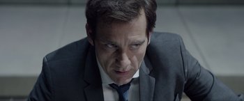 Movie still from “Anon” (2018), directed by Andrew Niccol – A person wearing a suit and tie; Close Up shot, Over the shoulder angle