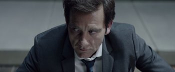 Movie still from “Anon” (2018), directed by Andrew Niccol – A person wearing a suit and tie; Close Up shot, Over the shoulder angle