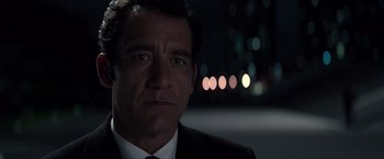 Movie still from “Anon” (2018), directed by Andrew Niccol – A person wearing a suit and tie; Close Up shot, Over the shoulder angle
