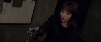 Movie still from “Anon” (2018), directed by Andrew Niccol – A woman in a black jacket holding a gun; Close Up shot, Over the shoulder angle