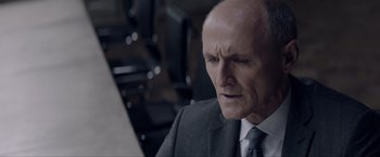 Movie still from “Anon” (2018), directed by Andrew Niccol – An older man wearing a suit and tie; Close Up shot, High angle