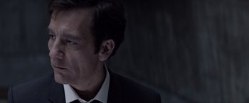 Movie still from “Anon” (2018), directed by Andrew Niccol – A person wearing a suit and tie; Close Up shot, Over the shoulder angle