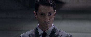 Movie still from “Anon” (2018), directed by Andrew Niccol – A person wearing a suit and tie; Close Up shot, High angle