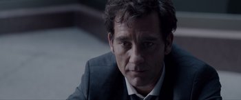 Movie still from “Anon” (2018), directed by Andrew Niccol – A person wearing a suit and tie; Close Up shot, Over the shoulder angle