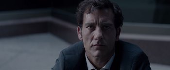 Movie still from “Anon” (2018), directed by Andrew Niccol – A person wearing a suit and tie; Close Up shot, Over the shoulder angle