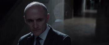 Movie still from “Anon” (2018), directed by Andrew Niccol – A man in a suit and tie standing in front of a window; Close Up shot, Over the shoulder angle