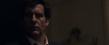 Movie still from “Anon” (2018), directed by Andrew Niccol – A person wearing a suit and tie; Close Up shot, Over the shoulder angle