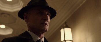 Movie still from “Anon” (2018), directed by Andrew Niccol – An older man wearing a hat and a tie; Close Up shot, Low angle