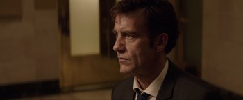 Movie still from “Anon” (2018), directed by Andrew Niccol – A person wearing a suit and tie; Close Up shot, Over the shoulder angle